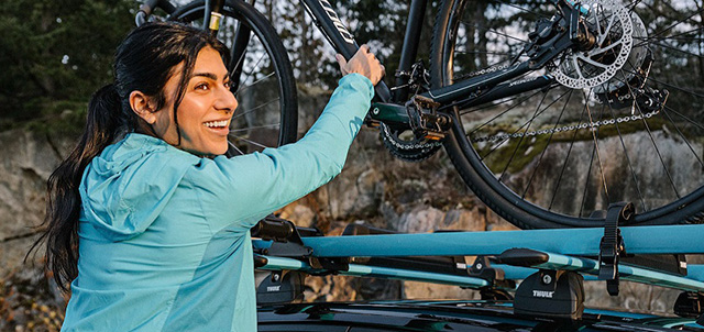 Woman loading a bike on to an Evo bike roof rack
